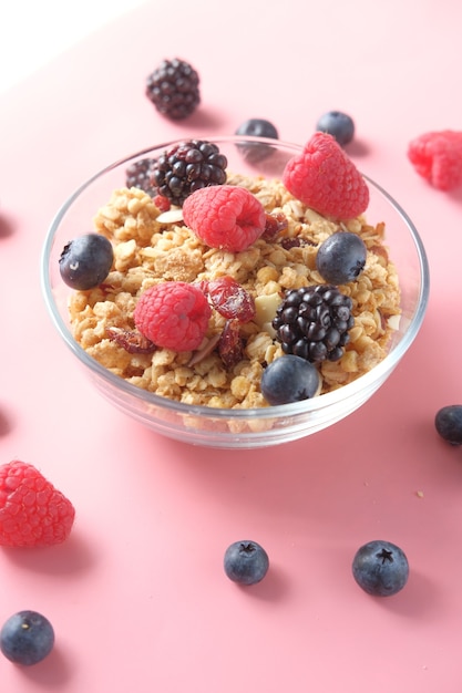 Granola et baies dans un bol sur une surface rose