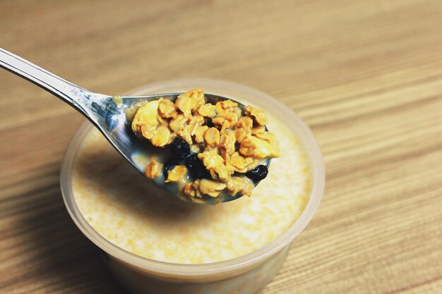 Granola sur la cuillère sur une tasse de lait