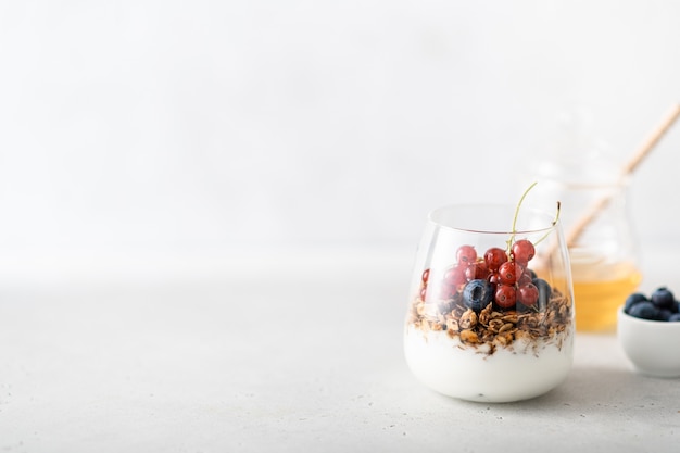 Granola avec du yogourt, des baies et du miel dans un verre