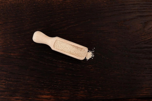 Granules de levure dans une cuillère en bois sur fond de bois marron foncé vue de dessus Espace de copie de mise au point sélective.