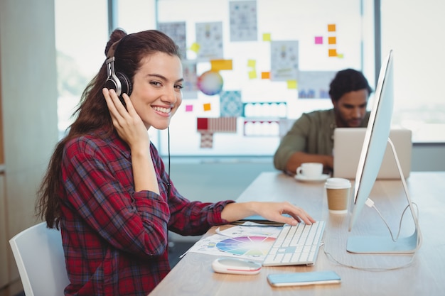 Graphiste femme travaillant tout en écoutant de la musique