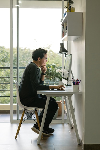 Graphiste indépendant réalisant un projet depuis son ordinateur. Bureau à domicile minimaliste.