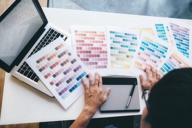 Graphiste et nuancier et stylos sur un bureau.