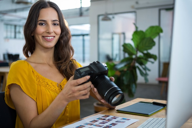 Graphiste souriant tenant un appareil photo numérique au bureau de création