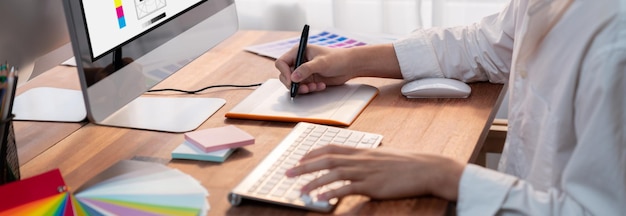 Le graphiste travaille sur un ordinateur portable avec un stylo numérique.