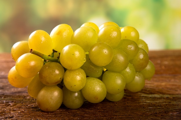 Grappe de raisin vert, fruits d'automne, symbole d'abondance sur fond de bois rustique.