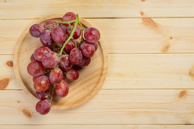 Grappes de raisins rouges mûrs frais sur la surface en bois.