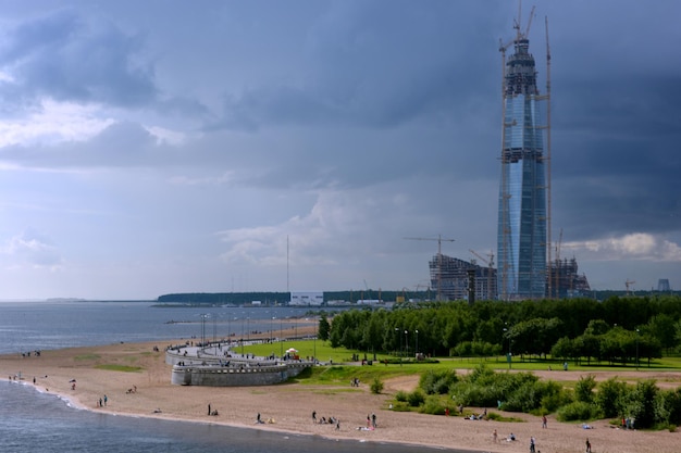 Photo un gratte-ciel en construction au bord de la mer sous le ciel passant du bleu à un orage