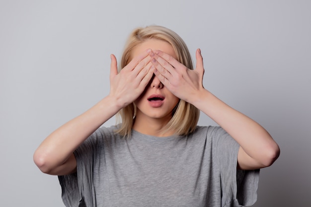 Grave femme blonde à lunettes sur mur blanc