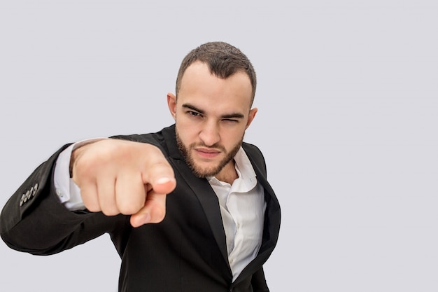 Grave jeune homme en costume pointe à la caméra. Il se rétrécit.