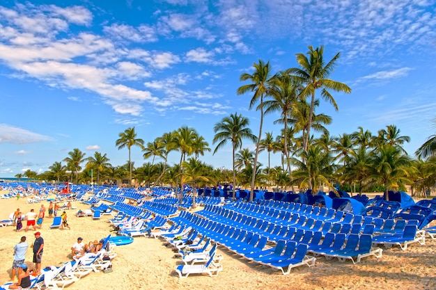 Great Stirrup Cay, Bahamas - - 08 janvier 2016 : plage publique avec de nombreuses personnes sur la côte sablonneuse près de palmiers verts et chaises journée ensoleillée en plein air sur fond de ciel bleu naturel