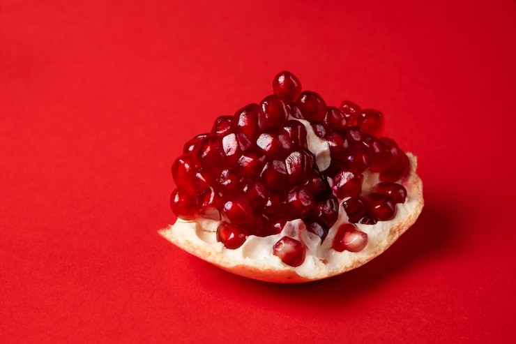 Photo grenade mûre cassée sur une surface rouge.