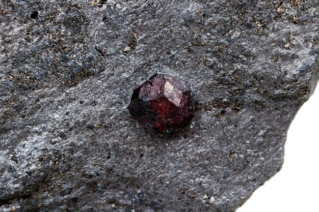 Grenat de pierre minérale de macro dans la roche sur un fond blanc