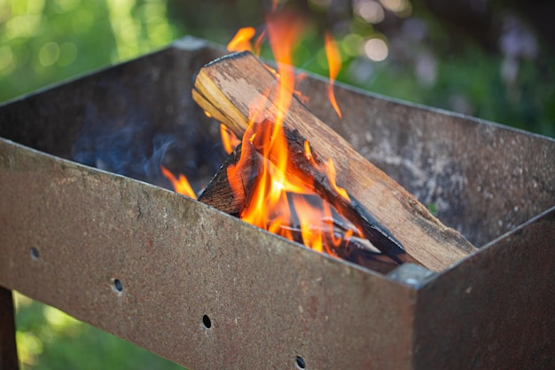 Gril de barbecue en métal rustique en plein air avec feu de bois de chauffage
