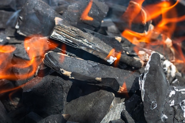 Photo grill de barbecue avec un feu ouvert brûlant et enflammé avec des briquettes de charbon chaud et des braises de flamme rouge