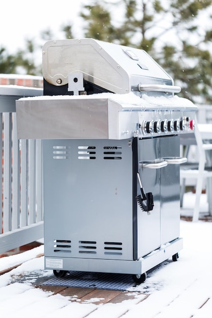 Grill extérieur couvert de neige sur le patio arrière résidentiel en hiver.