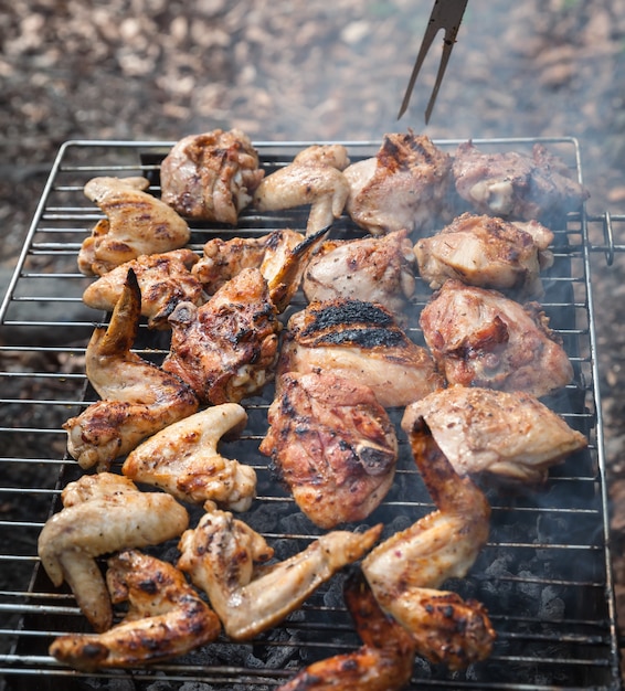 Griller du poulet épicé dans une grille sur un barbecue au charbon de bois. Shalow DOF.