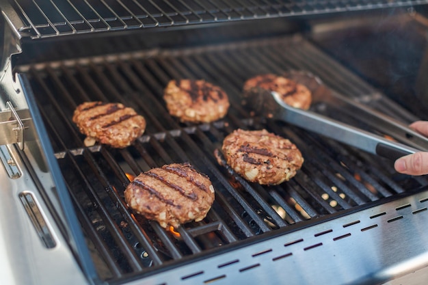 Griller des hamburgers classiques sur un gril à gaz extérieur en été.