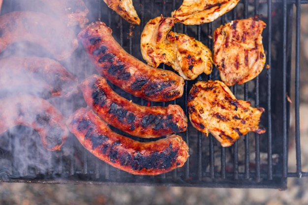 Griller des saucisses et des côtelettes de porc sur un barbecue au barbecue dans le jardin