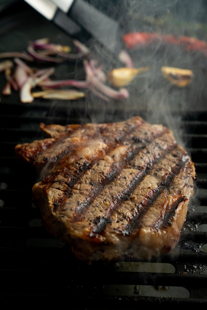 Photo griller un steak de faux-filet à la maison. fumée naturelle. grill d'été, concept de cuisine à la maison