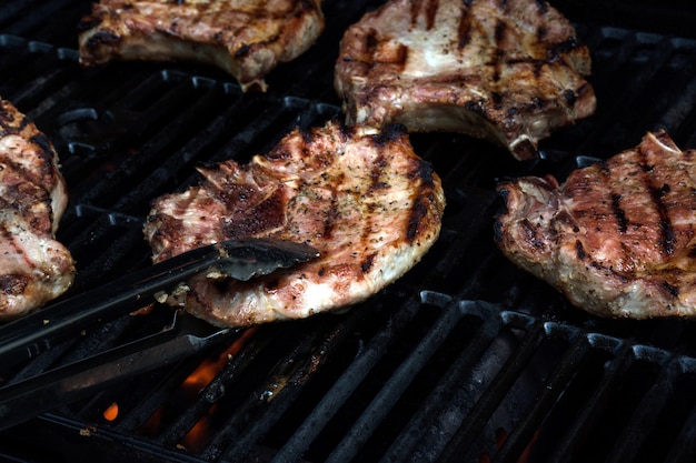 Griller des steaks sur un gril enflammé. Viande fraîche grillée.