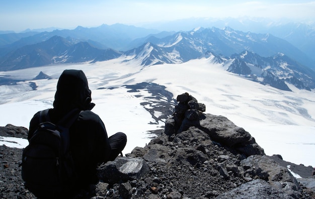 Grimpeur assis sur un sommet de montagne et regardant la superbe vue panoramique