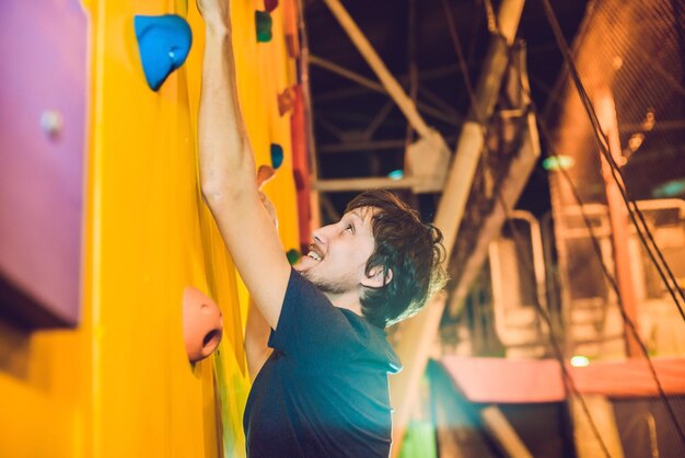 Grimpeur homme sur mur d'escalade artificiel en salle de bloc