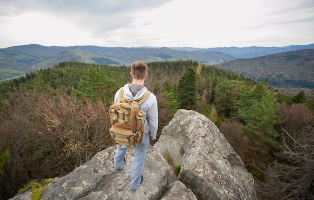 Grimpeur mâle avec sac à dos marron sur le sommet de la roche