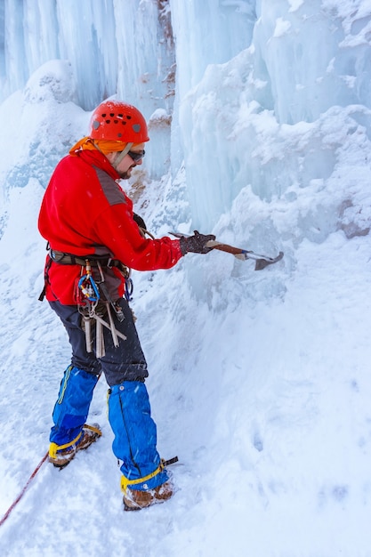 Un grimpeur avec un piolet coupe la glace, fait des pas dans le glacier