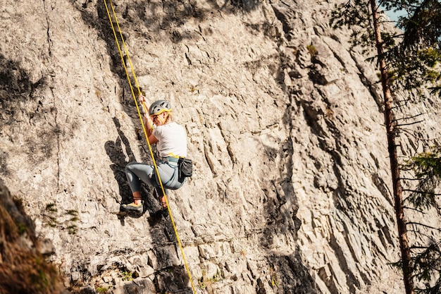 Grimpeur portant du matériel d'escalade Pratiquer l'escalade sur une paroi rocheuse Sports d'escalade et concept de bloc grimpeur grimpe sur une paroi rocheuse