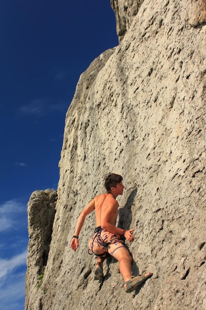 Grimpeur sur un rocher sur le fond du coucher du soleil