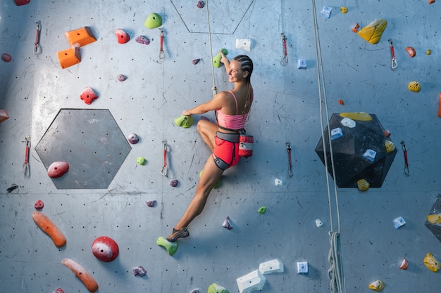 Le grimpeur s'entraîne sur un relief artificiel. Une femme monte un itinéraire d'escalade