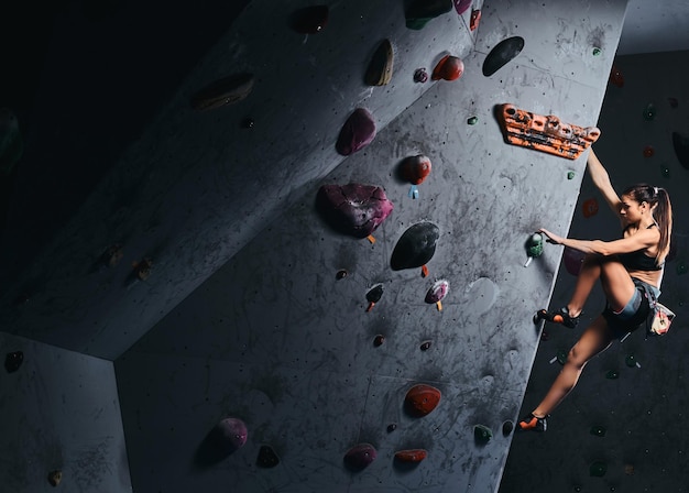 Grimpeuse professionnelle accrochée au mur de bloc, pratiquez l'escalade à l'intérieur.