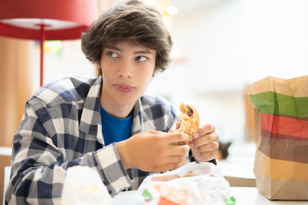 Grimy smudge drôle jeune homme mangeant de la malbouffe fast food