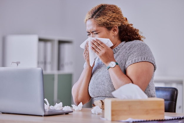 Grippe covid et employé d'entreprise malade souffrant d'un rhume ou d'une grippe travaillant sur un ordinateur portable se moucher ou éternuer dans un bureau Un jeune assistant souffre d'allergie aux sinus ou de symptômes de maladie
