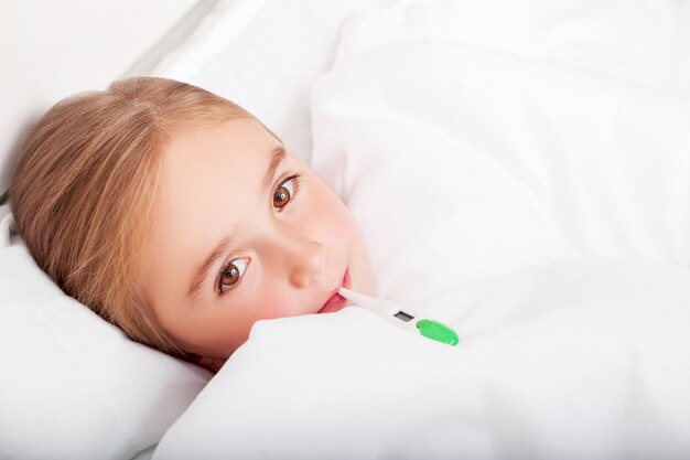 Grippe. Jeune fille au lit avec un thermomètre