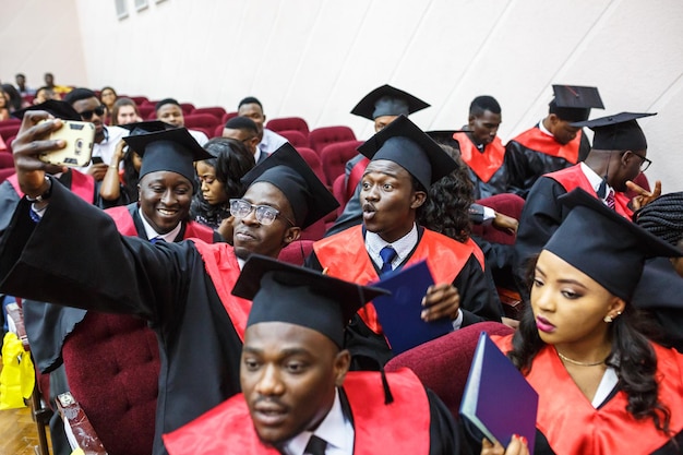 GRODNO BÉLARUS JUIN 2018 Étudiants en médecine africains étrangers dans des casquettes de graduation universitaires carrées et des imperméables noirs pendant le début des diplômes font du selfie
