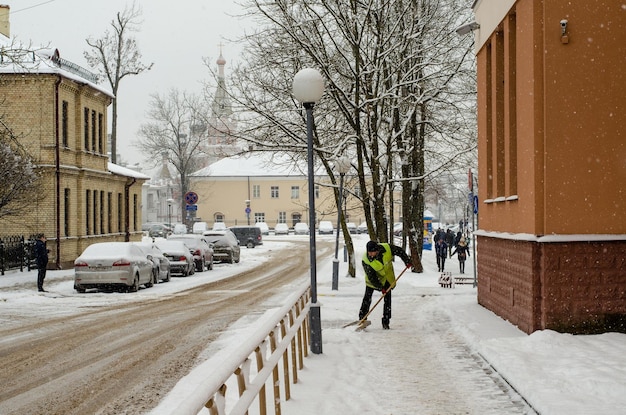 Grodno Bélarus 11 janvier 2019 Tempête de neige dans la ville Routes et trottoirs recouverts de neige Pelle de travailleur efface la neige Mauvais temps hivernal Nettoyage des rues après la tempête de neige