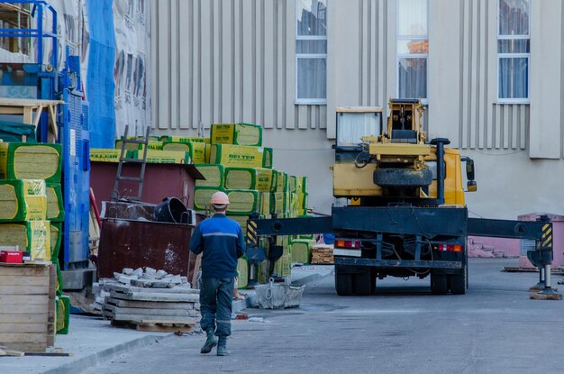 Grodno Belarus 11 octobre 2018 Un homme portant un casque et des vêtements de travail Réchauffement de la façade du bâtiment C'est une grue à tour A proximité se trouve un matériau de construction