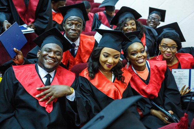 GRODNO BÉLARUS JUIN 2018 Étudiants en médecine africains étrangers dans des casquettes de graduation universitaires carrées et des imperméables noirs pendant le début des diplômes font du selfie