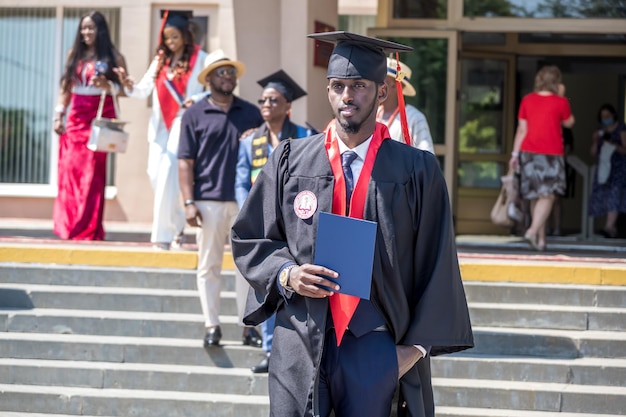 GRODNO BÉLARUS JUIN 2021 Heureux étudiants étrangers en médecine africains portant des casquettes de graduation universitaires carrées et des imperméables noirs au début des diplômes après la fin des études