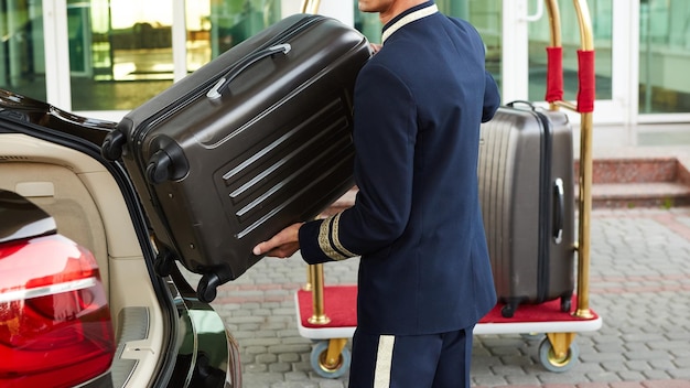 Groom emmenant les bagages de l'invité de ta voiture à sa chambre