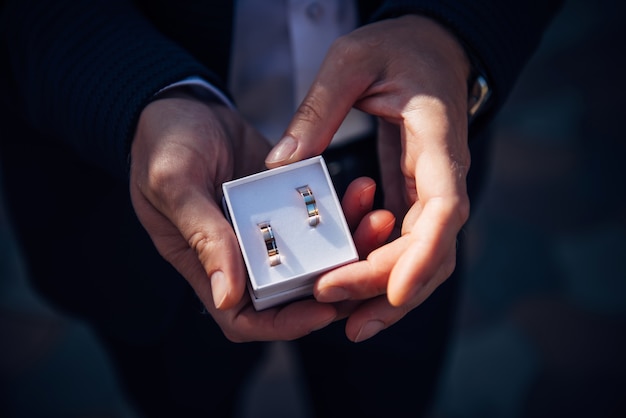 Groom holding petite boîte avec des anneaux de mariage en or