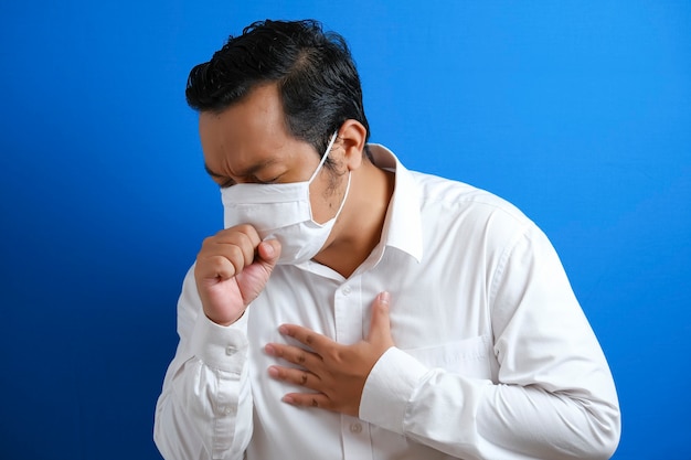 Un gros asiatique portant un masque tousse en fermant la bouche avec ses mains, il ne se sent pas bien. symptômes de la maladie à virus corona