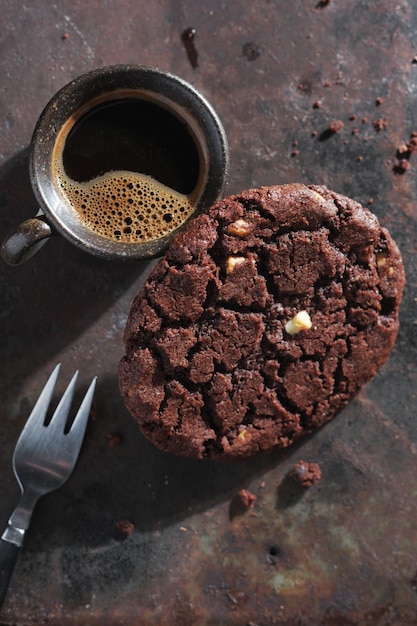 Un gros biscuit au chocolat et du café.