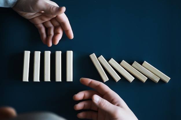 Gros bloc de bois domino épais dans une rangée arrêter la chute être stable dans le concept de solution d'entreprise de crise