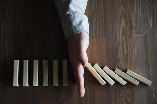 Gros bloc de bois domino épais dans une rangée arrêter la chute être stable dans le concept de solution d'entreprise de crise