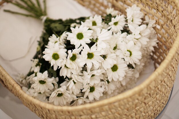 Un gros bouquet de marguerites dans un panier en paille.