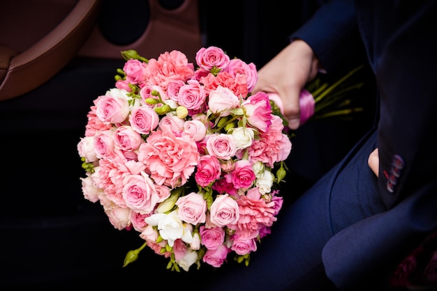 Gros bouquet de roses chez les hommes à la main dans la voiture