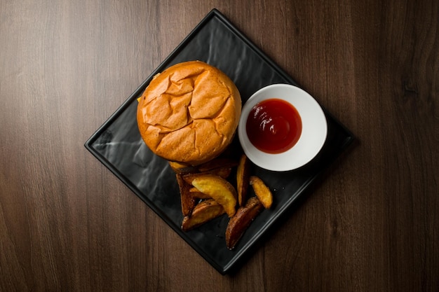 Gros burger frais avec sauce et frites sur plaque noire Menu burger classique américain